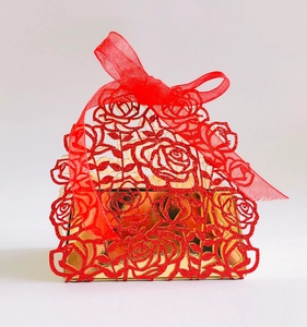 Detail of red glitter laser cut rose patterns and large mesh bow on a gold gift box