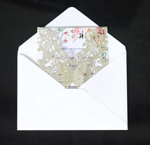 Detailed laser-cut gold glitter wedding invitation set with floral inner card and white envelope