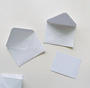 Minimalist white pearlescent paper envelope with matching blank card on warm background
