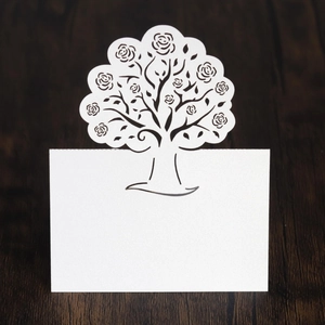 Macro shot of white laser-cut rose tree wedding place card with elegant pearl paper texture