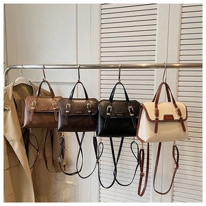 Detail view of four textured faux leather crossbody bags in various colors on hangers