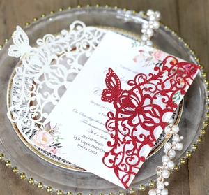 Detailed view of butterfly laser-cut wedding invitation set on a glass gold-beaded tray