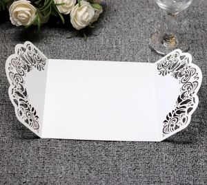 Detail of white laser-cut wedding invitation cover with intricate rose floral patterns