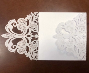 Macro detail of laser-cut wedding invitation with intricate lace hollow patterns