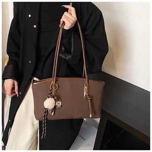 Detail of vintage brown tote bag with decorative ice cream charm and embossed logo texture