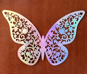 Detail of 3D laser-cut hollow butterfly sticker with iridescent holographic effect on wood