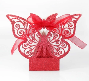 Detail of red glitter butterfly paper favor box with laser-cut patterns and red ribbon bow