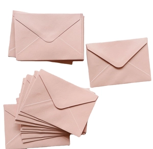 Detailed view of stacked rose pink pearlescent paper envelopes for wedding invitations