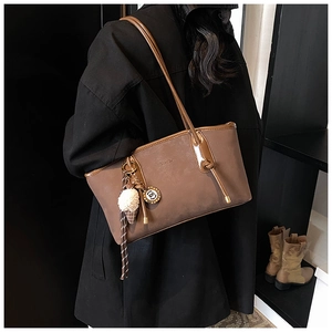 Detail of coffee brown tote bag featuring a plush ice cream charm on the side strap