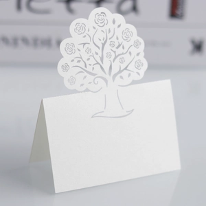 Macro shot of laser-cut tree design with rose patterns on pearlescent paper table card
