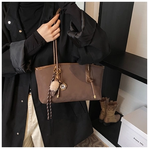 Detail of dark brown matte leather tote bag with logo embossing and decorative charms