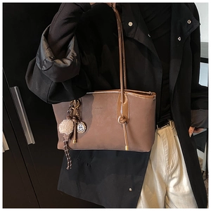 Detail view of large dark brown tote bag with suede texture and plush charm