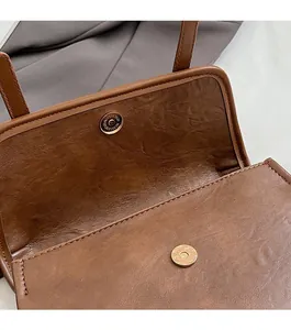 Close-up of dual metal magnetic buckles and leather texture on a vintage brown backpack