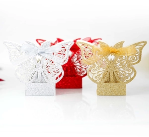 Detailed laser-cut butterfly favor boxes with glitter texture and silk ribbons