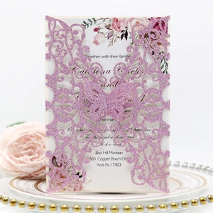 Detail of pink glitter laser-cut butterfly invitation with floral insert and gold-rimmed plate