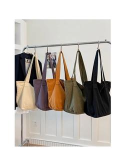 Close-up of five colorful canvas tote bags hanging on a rack for daily commute