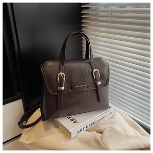 Detailed shot of dark brown vintage faux leather handbag on art books and soft clothing