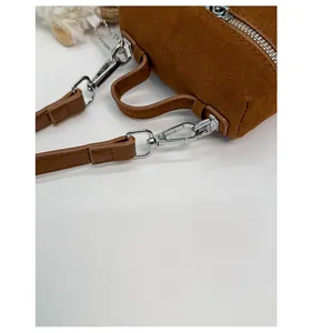 Close-up of detachable silver metal buckle and brown suede strap on fashion handbag