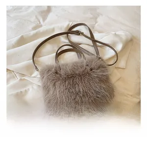 Detail view of khaki faux fur handbag texture with golden hardware and leather strap