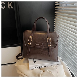 Detail of vintage brown tote bag with metal buckle straps and golden logo on soft fabric