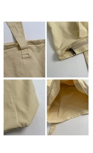 Detail view of reinforced stitching, zipper, and wide interior of a beige canvas tote bag