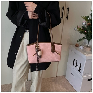 Detail of pink suede tote bag with brown leather handles and plush ice cream charm