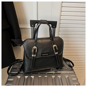 Detail of vintage black leather bag featuring gold buckles on a stylish metal suitcase