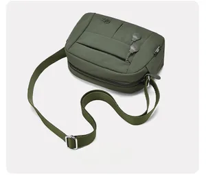 Top-down view of a dark green nylon crossbody bag with layered zipper pockets