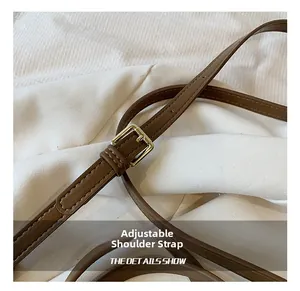 Macro detail of adjustable brown leather shoulder strap with gold-tone buckle hardware