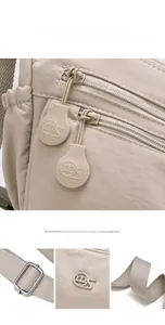 Detail der hellbeigen Nylon-Umhängetasche mit Reißverschlüssen und verstellbarem Web-Schultergurt