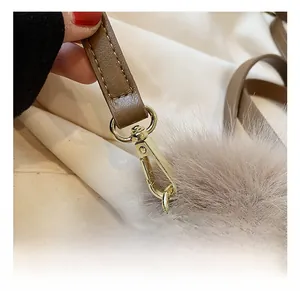 Detailed view of gold metal swivel hook with brown PU leather strap and grey fur ball