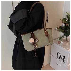 Detail of green suede tote bag featuring brown leather straps and plush ice cream charm