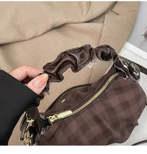 Close-up of brown checkerboard fabric bag with ruched leather handle and gold hardware