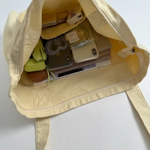 Detail view of large capacity canvas tote bag with zipper closure and inner pocket