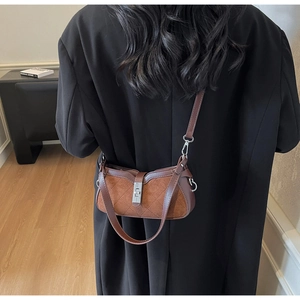 Dettaglio di una borsa a tracolla marrone bicolore con motivo trapuntato e fibbia argentata