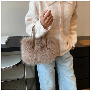 Close-up of soft camel faux fur handbag with leather handles held by a model