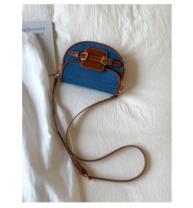 Detailed top view of a color-block saddle bag with denim fabric and brown leather straps