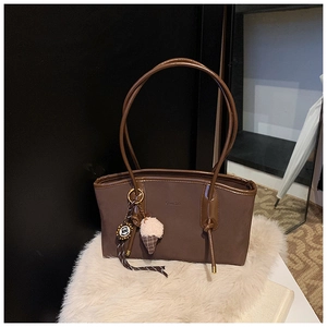 Detail of dark brown faux leather tote bag with slim handles and a plush ice cream charm