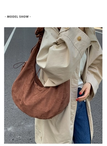 Brown suede hobo tote bag shown on a model wearing a beige trench coat outdoors