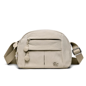 Detail view of beige nylon crossbody bag with zipper pocket and adjustable strap
