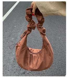 Detail view of brown suede tote bag with ruched handle and smooth matte texture