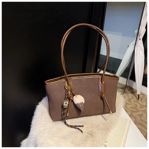 Detail of mocha brown tote bag featuring plush ice cream charm and braided strap detail