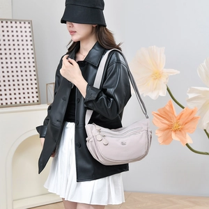 Nahaufnahme der hellbeige Nylon-Umhängetasche mit Reißverschlüssen und breitem Gurt am Modell
