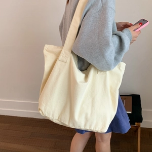 Model view of large canvas tote bag in off-white featuring wide shoulder straps for comfort