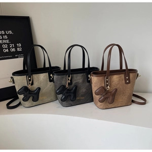 Detailed view of three marble-textured bucket bags with cute puppy charms and top handles