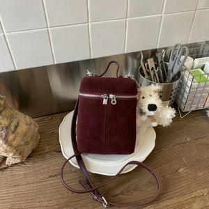 Detail of vintage burgundy frosted suede crossbody bag with dual silver zippers and stitching