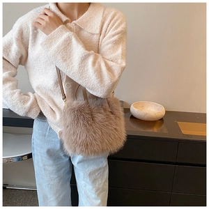 Close-up of soft beige faux fur crossbody bag with thin leather strap on a model