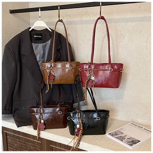 Detail of four glossy leather tote bags in brown, red, coffee and black with bear charms