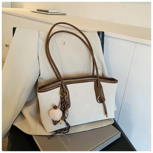 Close-up of cream vintage tote bag with contrast brown trim and plush charm detail