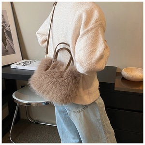 Detailed close-up of soft plush texture and leather strap on a camel faux fur handbag